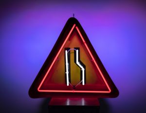 neon road sign - the road narrows